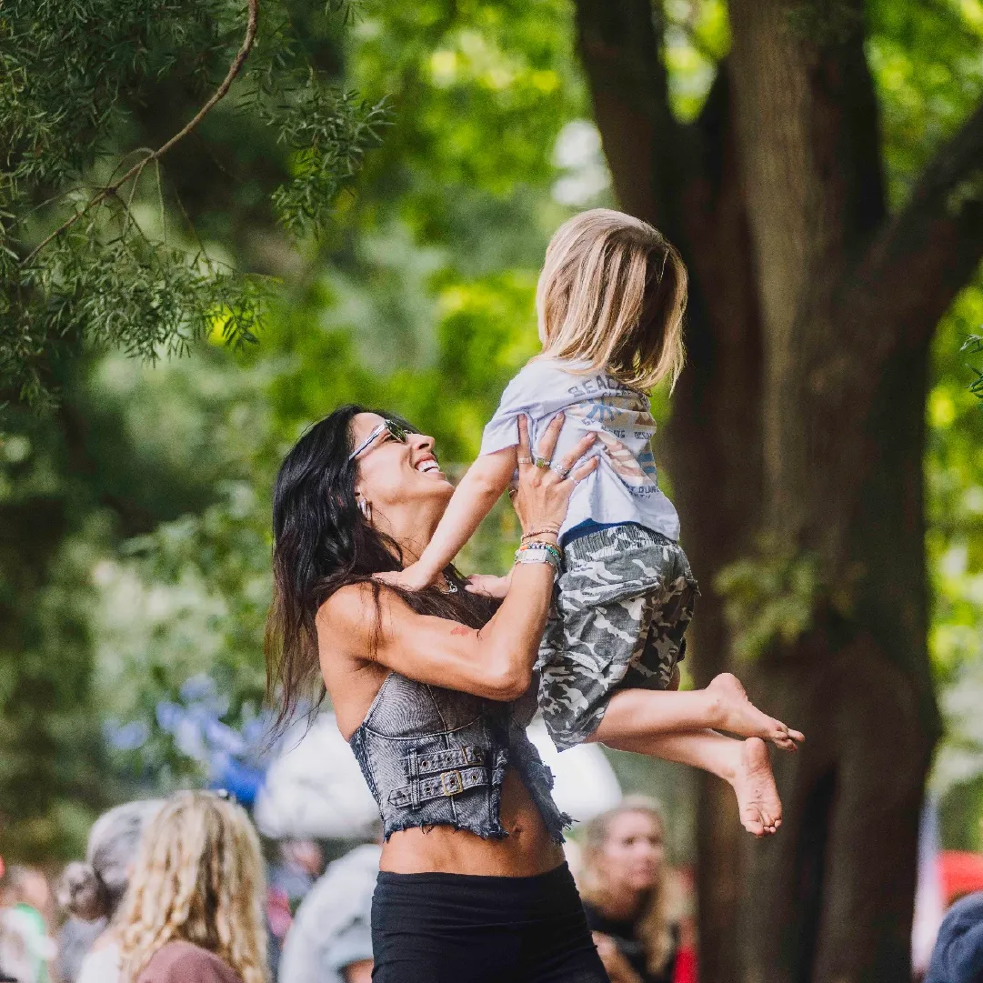 A photograph of a woman holding up her child in the air playfully.