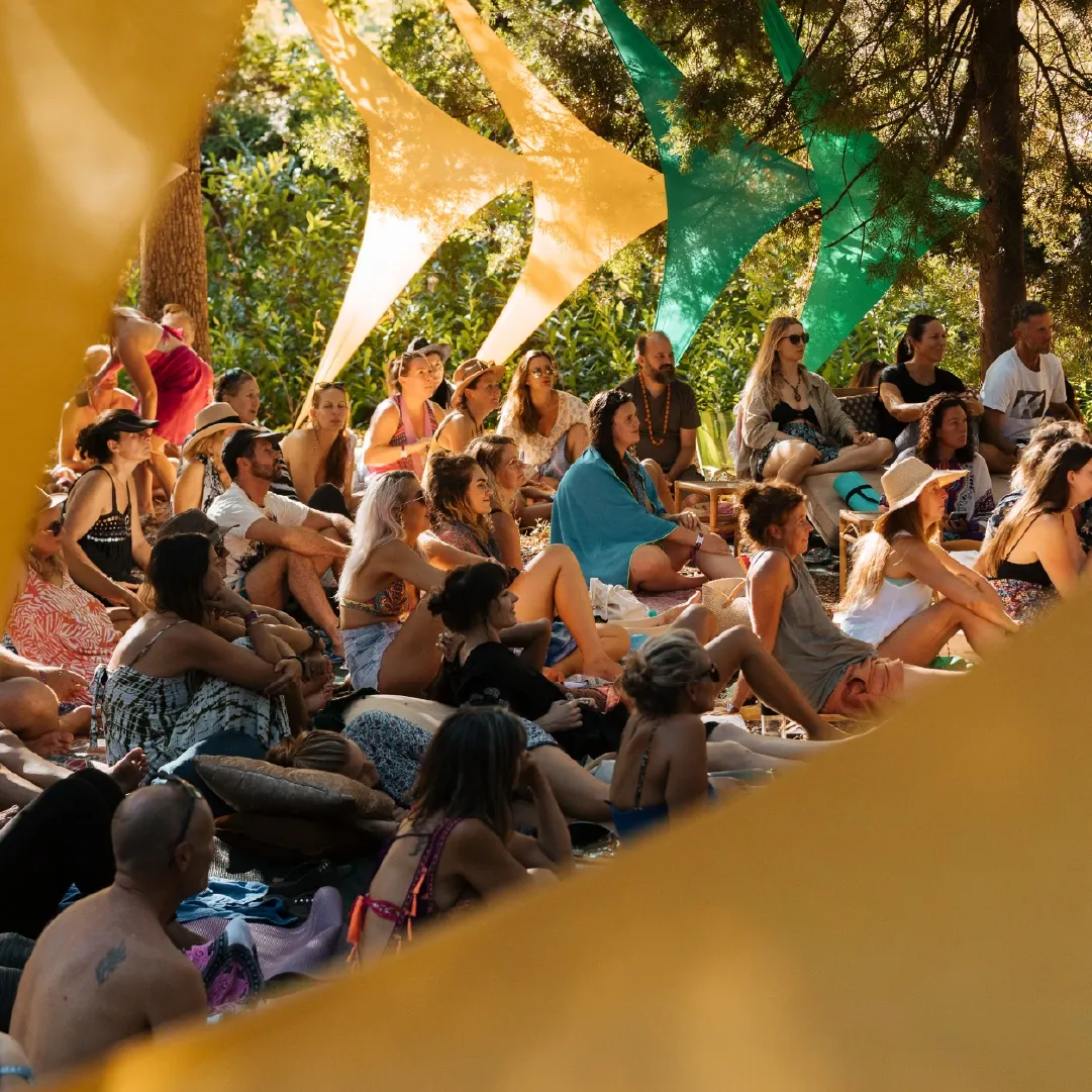 A photograph of people sitting and watching a performance during the day at Retreat Yourself