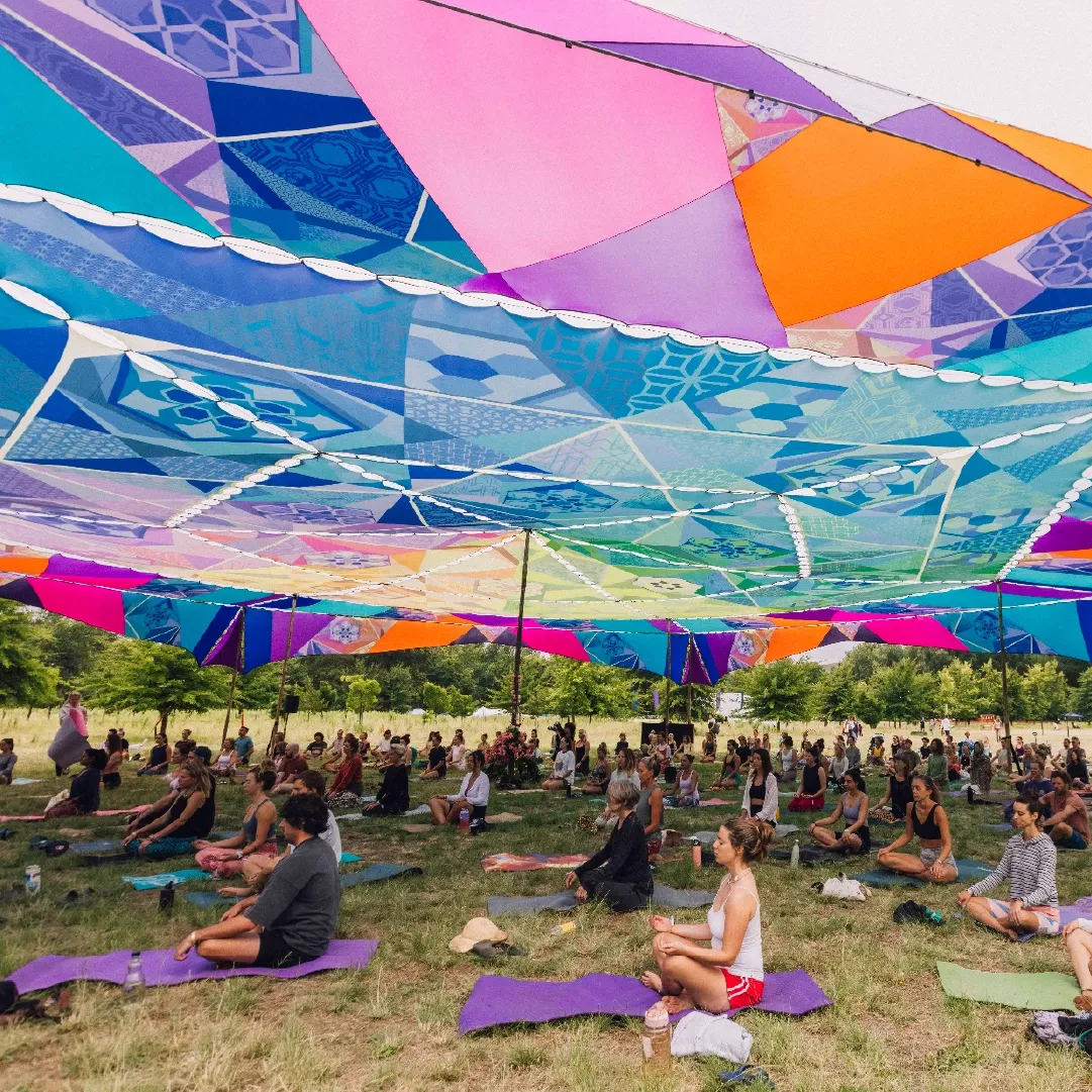 A photograph of people meditating underneath a covering at Retreat Yourself.