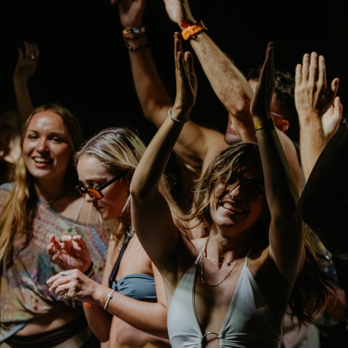 A crowd dancing with their hands in the air at night