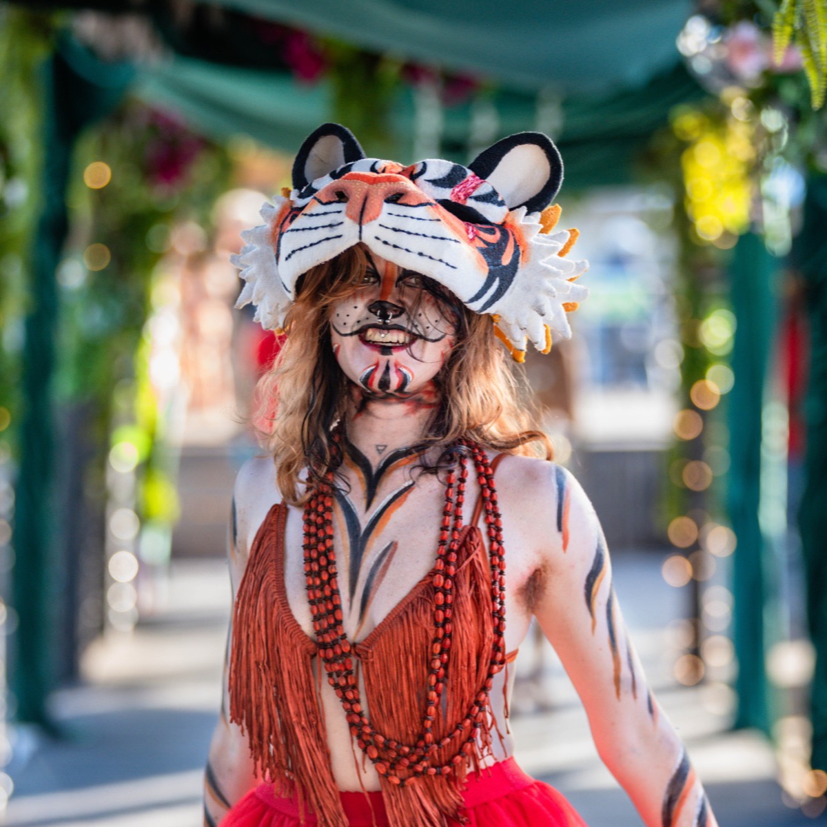 A festival-goer in a tiger mask and fringed costume