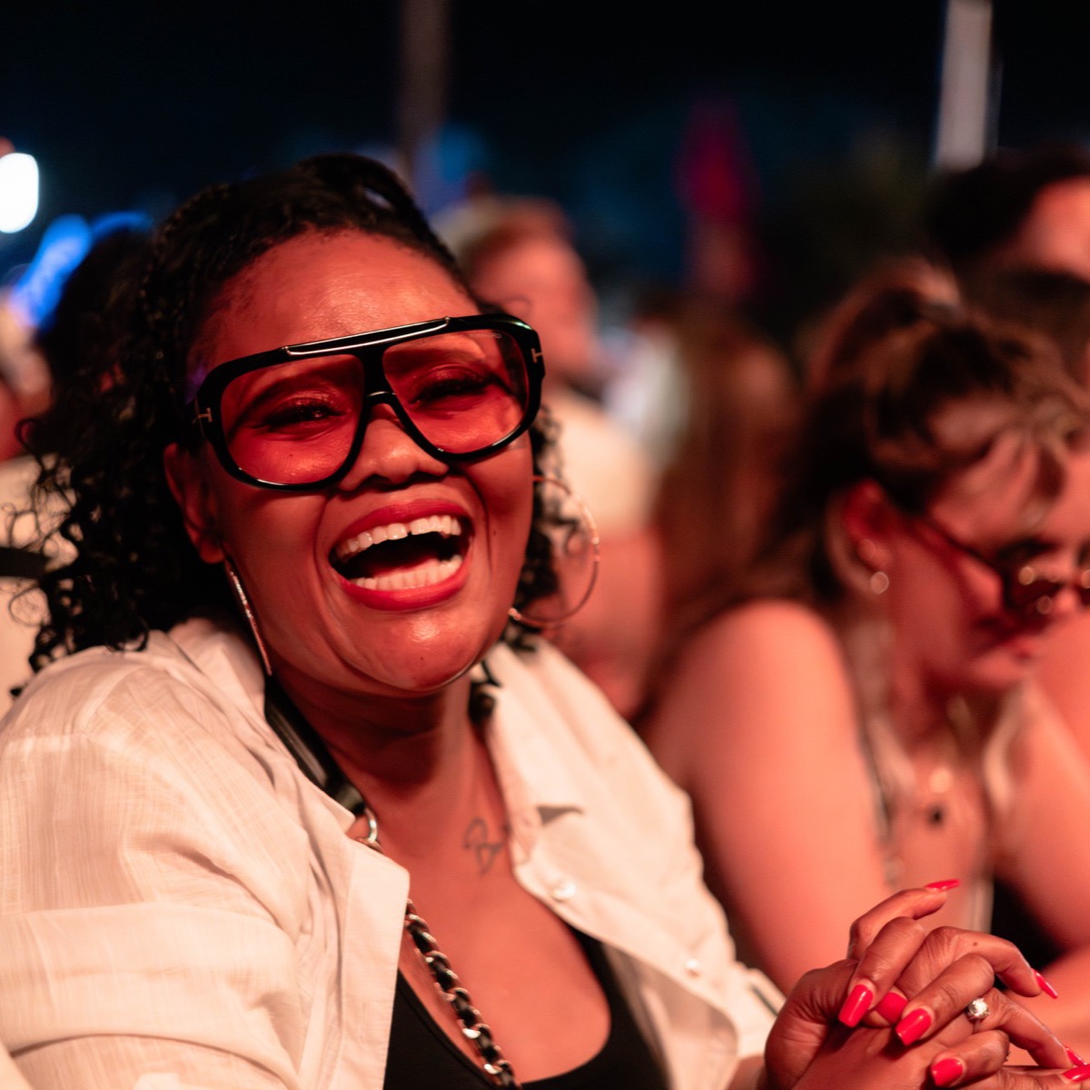 A smiling festival-goer in red sunglasses on the dancefloor